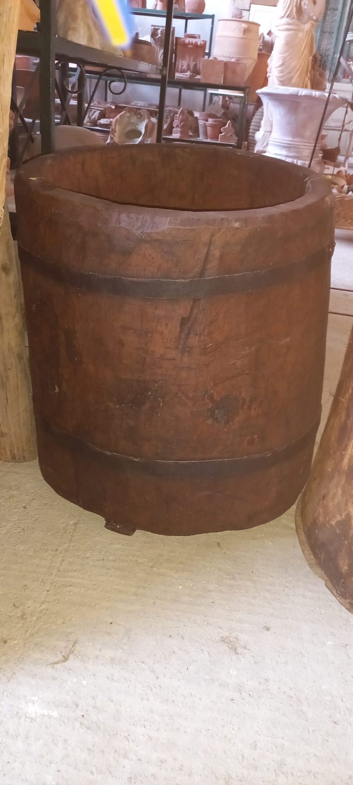 big old wooden bucket , handmade out of big tree trunk curved from the inside ,with metal rings