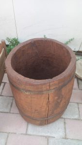 big old wooden bucket , handmade out of big tree trunk curved from the inside ,with metal rings