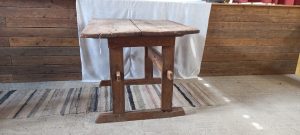 old wooden table, in dark colored wood, handmade ,restored, with an original setting of the base with a part of an old wine/tobacco press