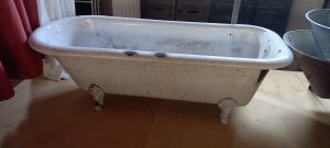 old cast iron  free standing bath tub, with four legs, rounded on the edges, white colored, heavy piece, retro style