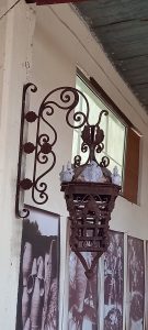 old iron wall light with spirals and leaf decoration and white details (medusa face and flower buds), with an iron wall support decorated also with spirals and rosettes, old iron lantern, handmade, impressive piece elaborately decorated