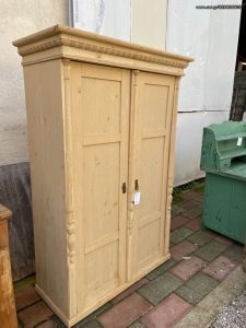 old wooden wardrobe in a light yellow color, closet , old wooden clothes closet with a top shelf and a rod for hanging clothes, vintage-rustic decoration