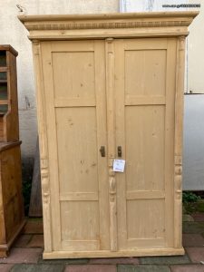 old wooden wardrobe in a light yellow color, closet , old wooden clothes closet with a top shelf and a rod for hanging clothes, vintage-rustic decoration