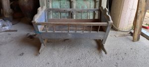old baby cot- cradle , old handmade baby cot in a grey cot
