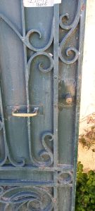 old iron door with spirals and twirls and an oval arch on the top part, solid iron in blue color, heavy external barred door, garden door, iron garden gate, heavily built, handmade